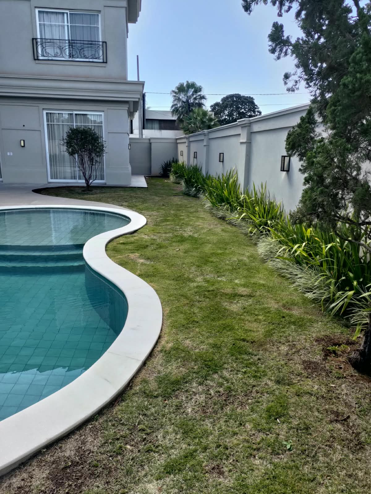 Borda de piscina com gramado perfeito e plantas de canteiro